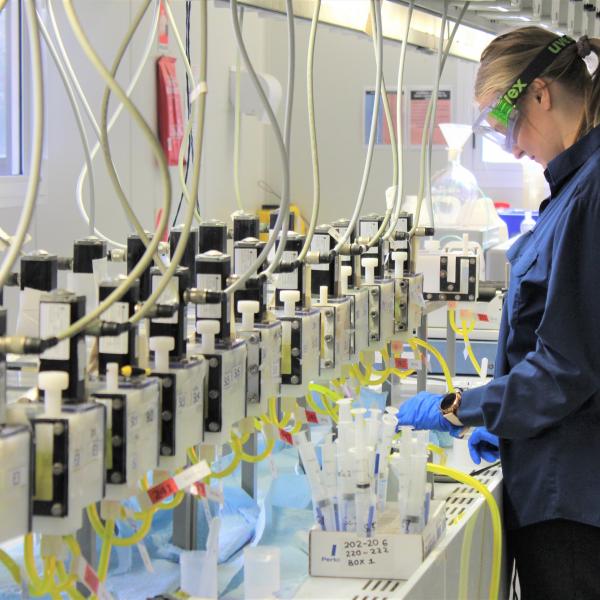 A scientist wearing googles is overseeing experiments in a laboratory.