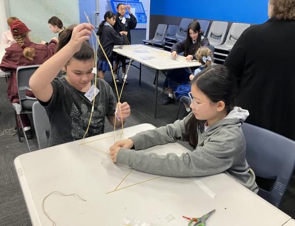 Two girls building a spaghetti tower