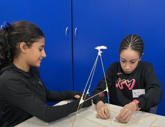 Two girls building a spaghetti tower